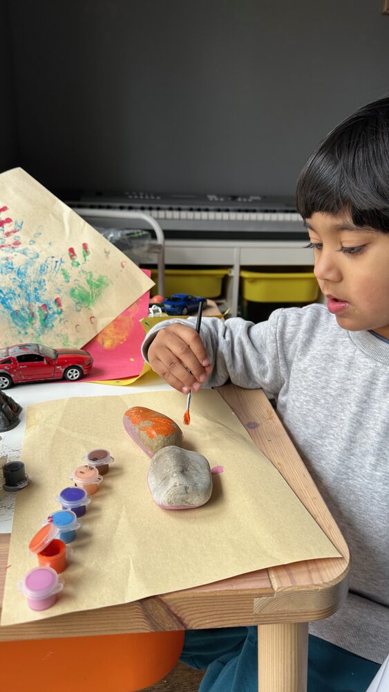 Kedaar painting rocks at a craft table