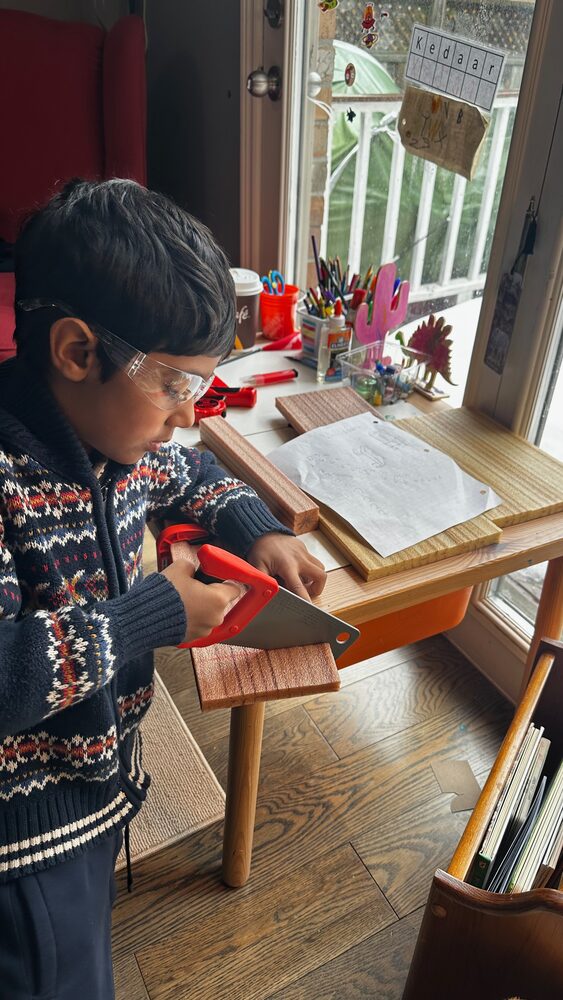 Kedaar wearing safety goggles working with wood and tools